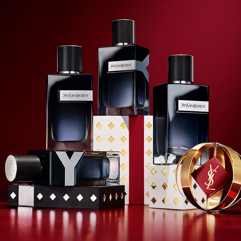 YSL Y Eau de Parfum bottles stacked on black, white, and gold Holiday gift boxes.
