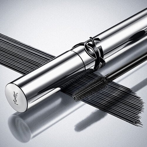 YSL Lash Clash mascara on a reflective surface, showcasing the bold black texture and couture packaging.