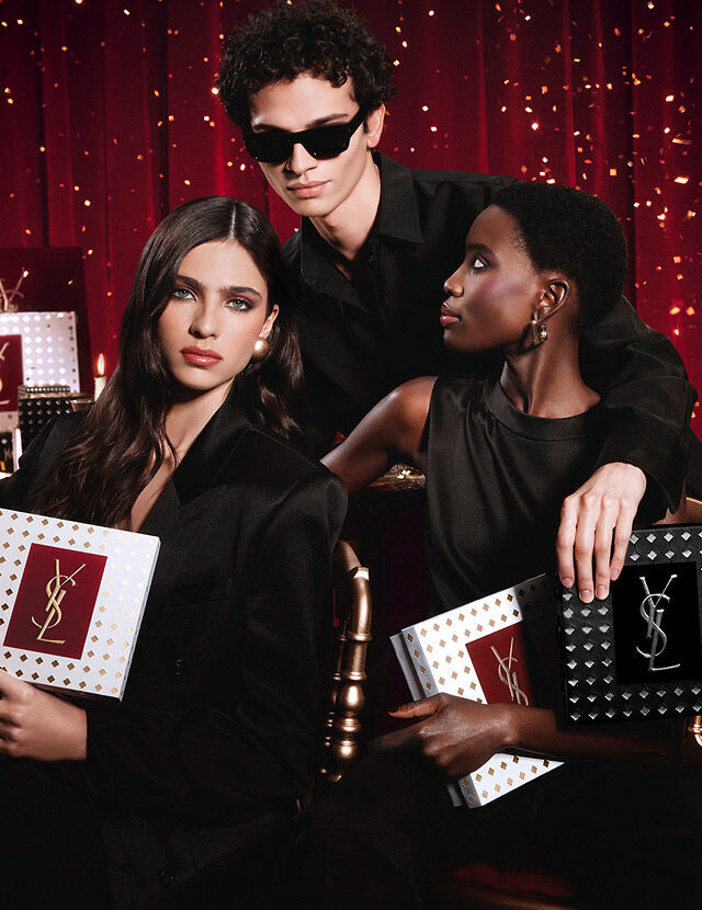 Models posing together holding luxury YSL Holiday gift boxes in a festive atmosphere.