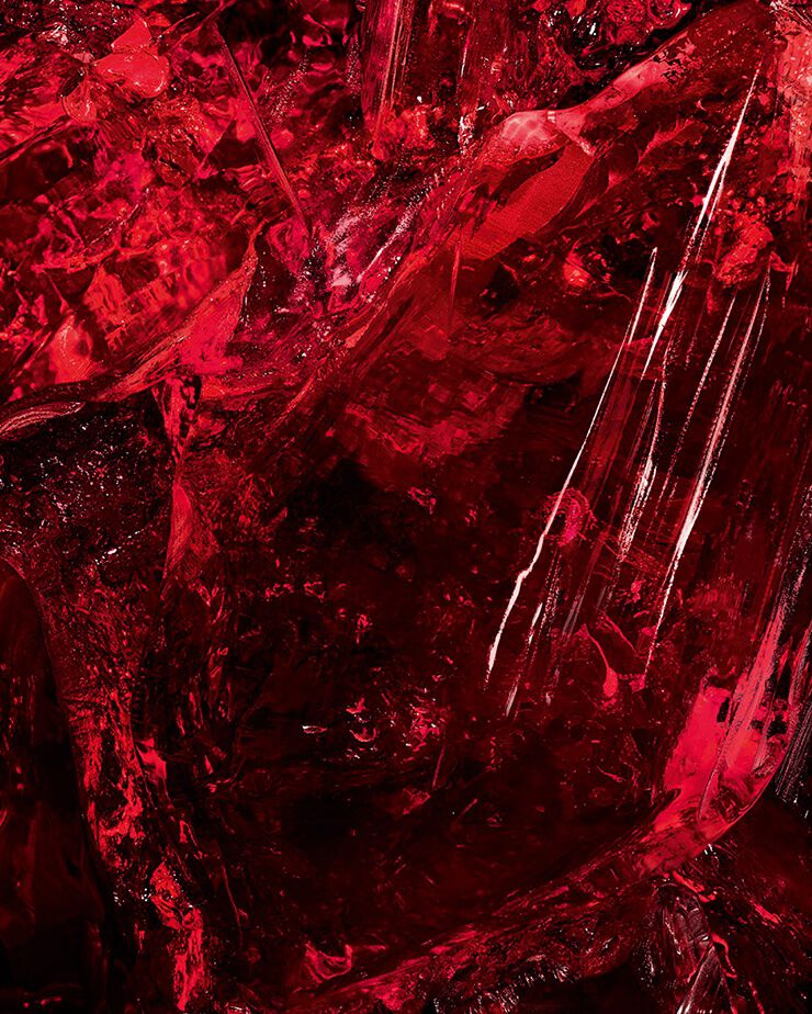 Macro shot of textured red amber
crystal, a key ingredient of CŒUR Eau
de Parfum by YSL, showing its raw
depth.