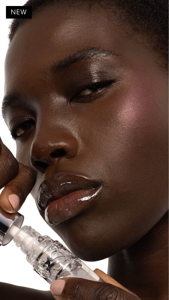 Nyaluak, deep-skinned, with YSL LOVESHINE Plumping Lip Oil Gloss in Shade 11 Radiant Glass, showcasing glossy lips.