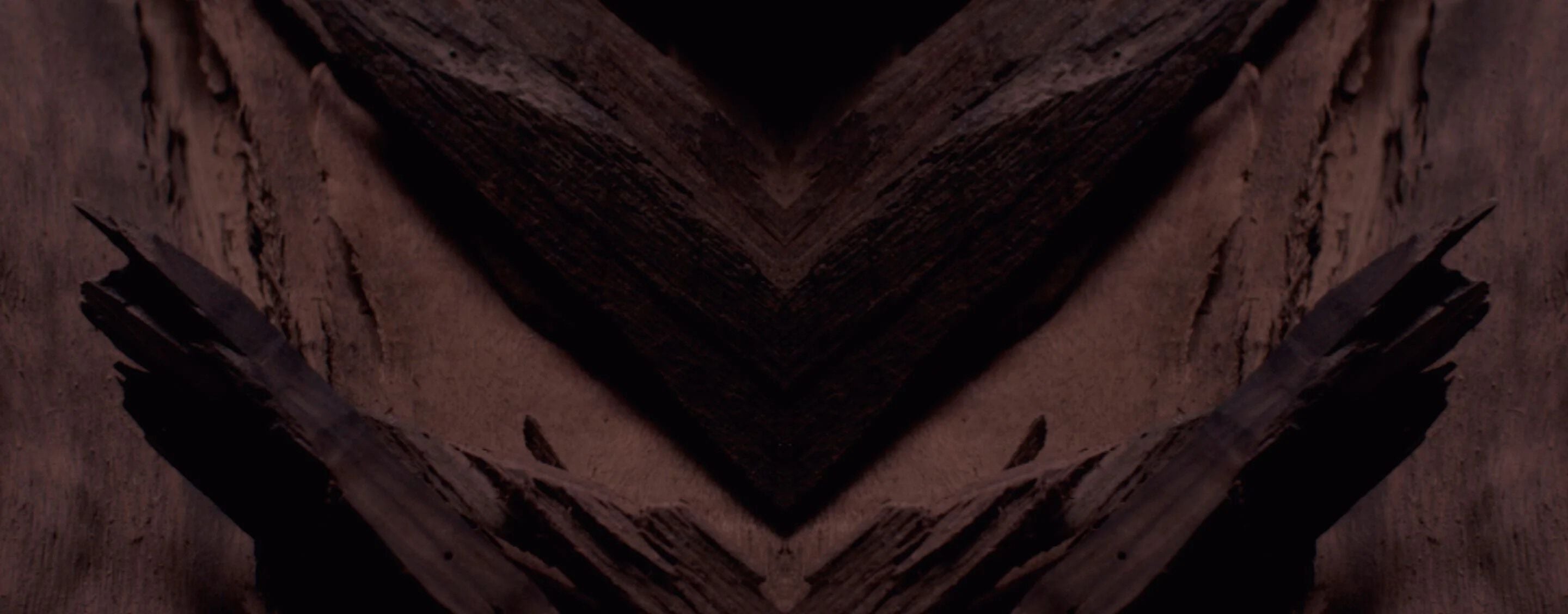 Dark, textured background with a prominent chevron pattern in
deep browns and blacks, designed for YSL LVP Extrait de Parfum
product display.