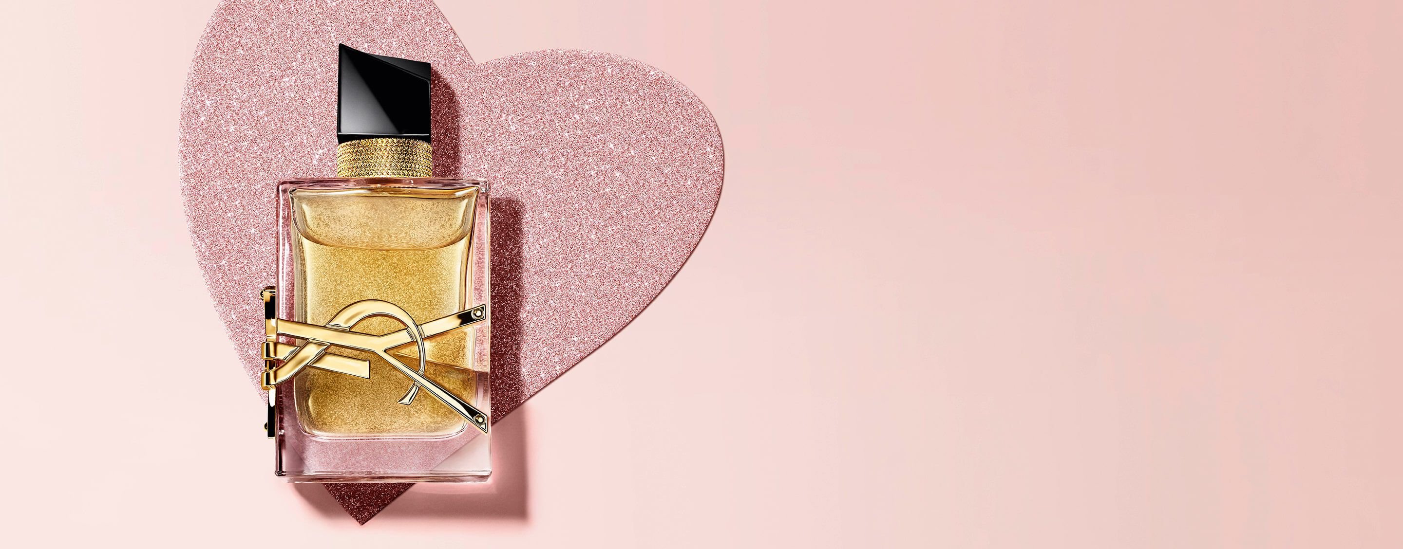 YSL Libre Eau de Parfum, a gold-toned bottle with
the YSL logo, on a glittery heart background.
