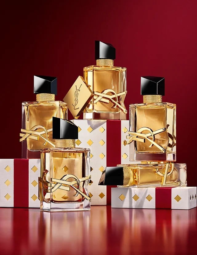Multiple YSL LIBRE fragrance bottles layered over luxury gold-patterned Holiday gift packaging.