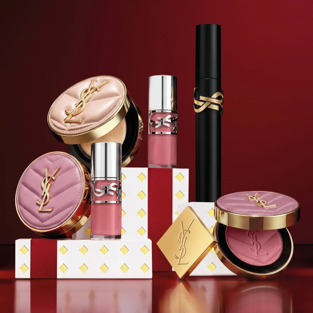 Multiple YSL LIBRE fragrance bottles layered over luxury gold-patterned Holiday gift packaging.